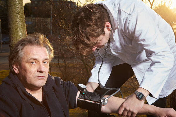 Пожилой человек чувствовал себя во время пробежки в парке. Парамедик осматривает его в полевых условиях
