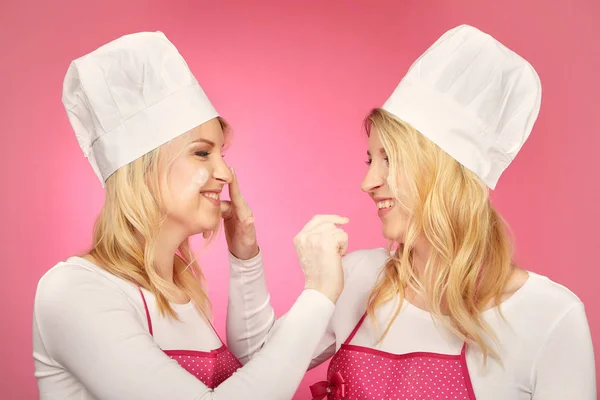 Nice blonde twins baking cakes posing for portrait