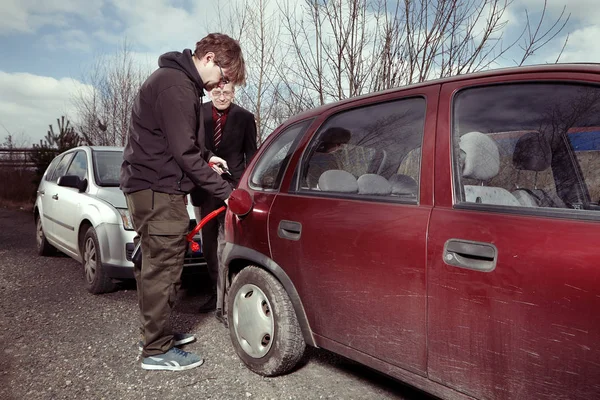 Driver filling empty tank with colleagues gasoline from reserve canister