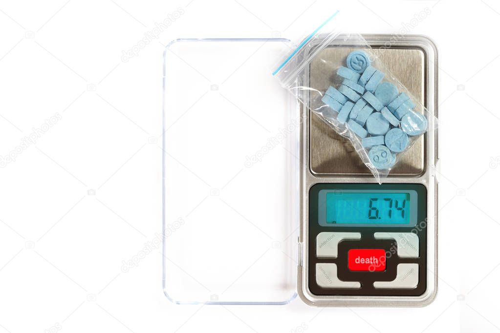 Pills of MDMA synthetic drugs on small digital scale