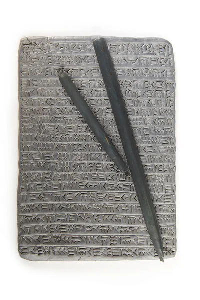 Ancient type of Akkad empire style cuneiform writing in gray clay with writing tools