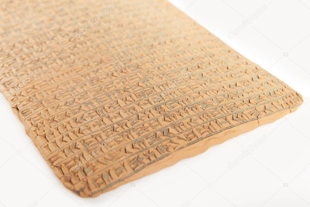 Ancient type of Akkad empire style cuneiform writing in brown clay with rest of dirty sand