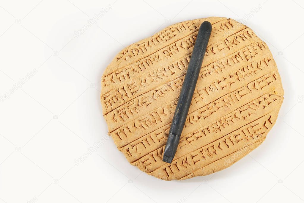 Ancient type of Akkad empire style cuneiform writing in brown clay with writing tool