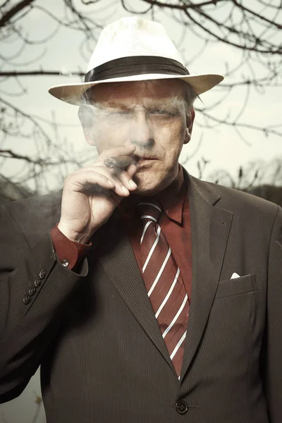 Bad evil man in mob style smoking cigar outdoor