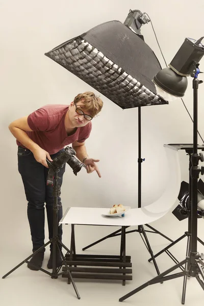 Male photographer in studio shooting food on plate