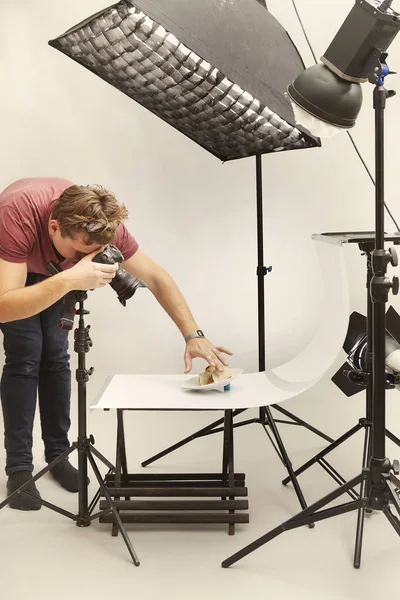 Male photographer in studio shooting food on plate