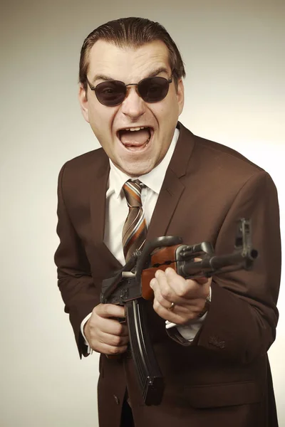 スーツ姿の男が自動銃でポーズ — ストック写真