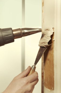 Man at home removing havy layer of old paint from door clipart