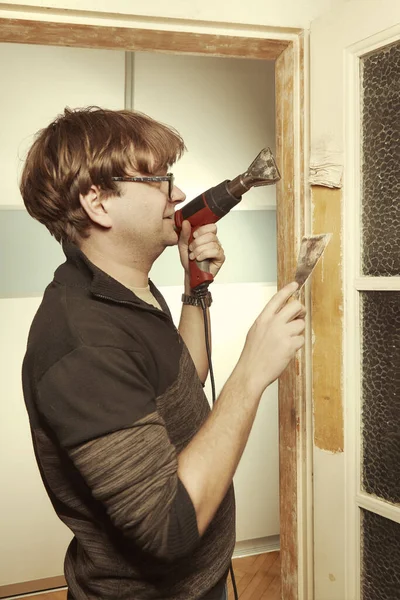 家の男はドアから古い塗料の重い層を削除 — ストック写真