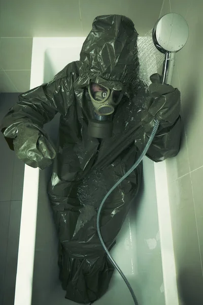 Ugly man in bathroom dressed to protective suit and mask showering