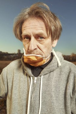 Güneşli bir günde toplum içinde yüz maskesi takmaktan mutsuz bir adam.