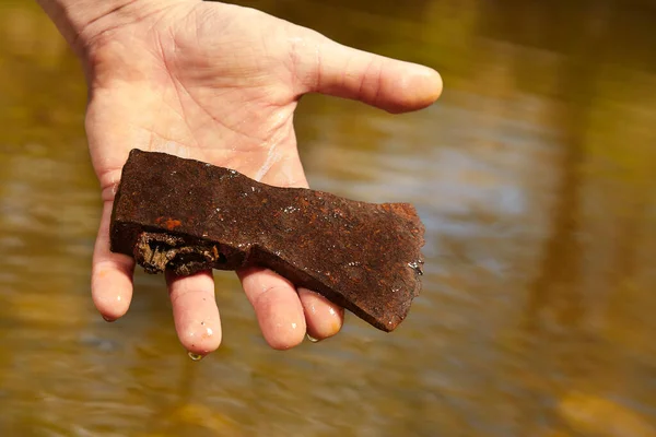 人类用磁铁在河水中发现了生锈的铁斧 — 图库照片