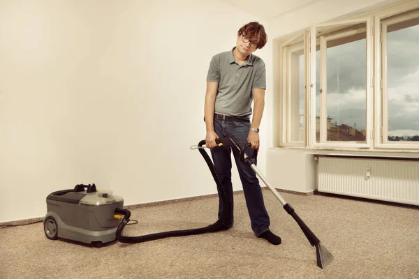 Caucasian man cleaning deeply carpet with wet cleaning machine