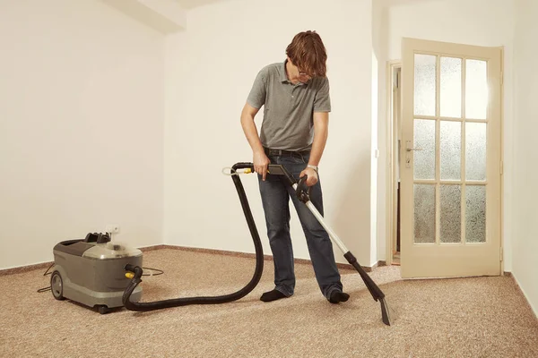 Caucasian man cleaning deeply carpet with wet cleaning machine