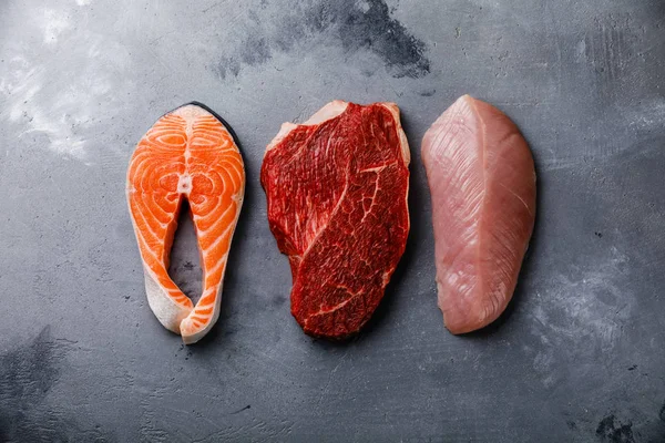 Raw food Salmon oily fish steak, beef meat and turkey breast on gray concrete background — Stock Image Raw Food Salmon Oily Fish Steak Beef Meat Turkey Breast Stock Photo