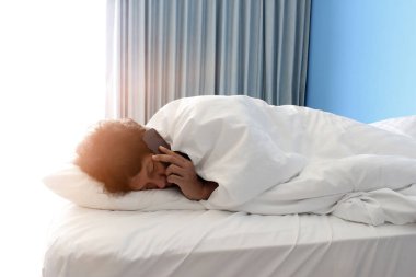 Adam yatakta uyuyor ve akıllı telefon kullanıyor.