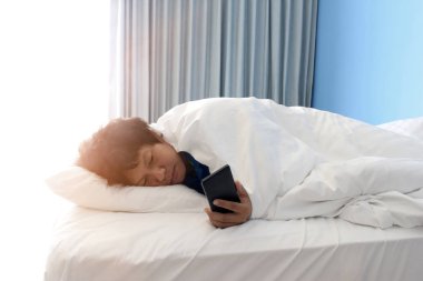 adam yatakta uyku ve bir akıllı telefon tutan