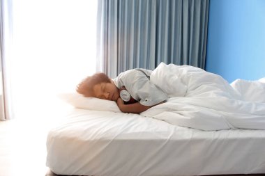 otel yatak odasında yatakta saat ile uyuyan adam