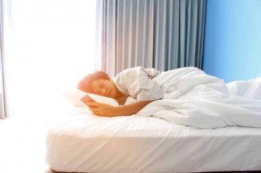 adam yatakta uyku ve bir akıllı telefon tutan