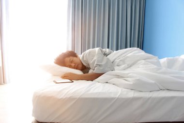 adam yatakta ve bir akıllı telefon uyku