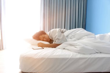 adam yatakta ve bir akıllı telefon uyku