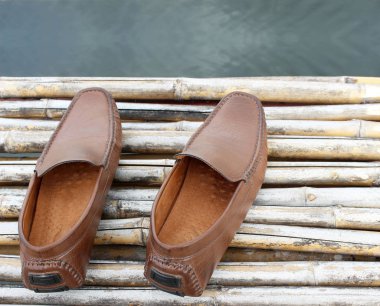 Gölet üzerinde kahverengi ayakkabı bambu ahşap üzerine