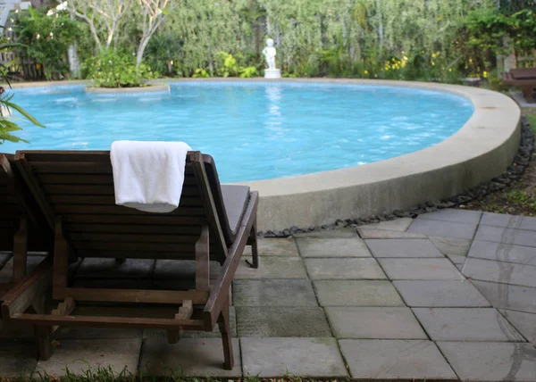 Plaj sandalyeleri yakınındaki yüzme havuzu havlu ile