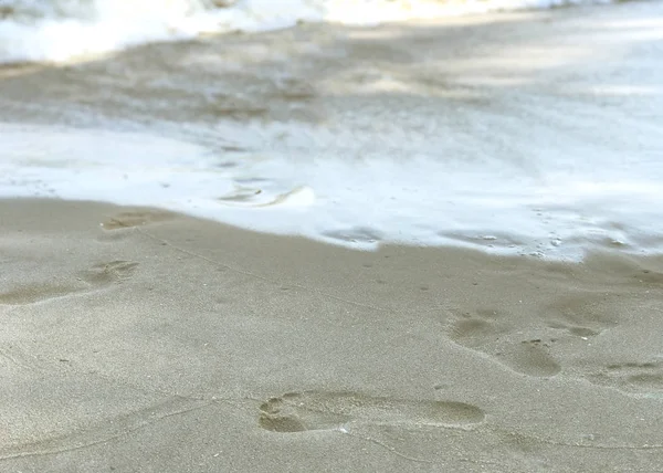 Słoneczny dzień brzeg morza i ślady stóp na piasku — Zdjęcie stockowe