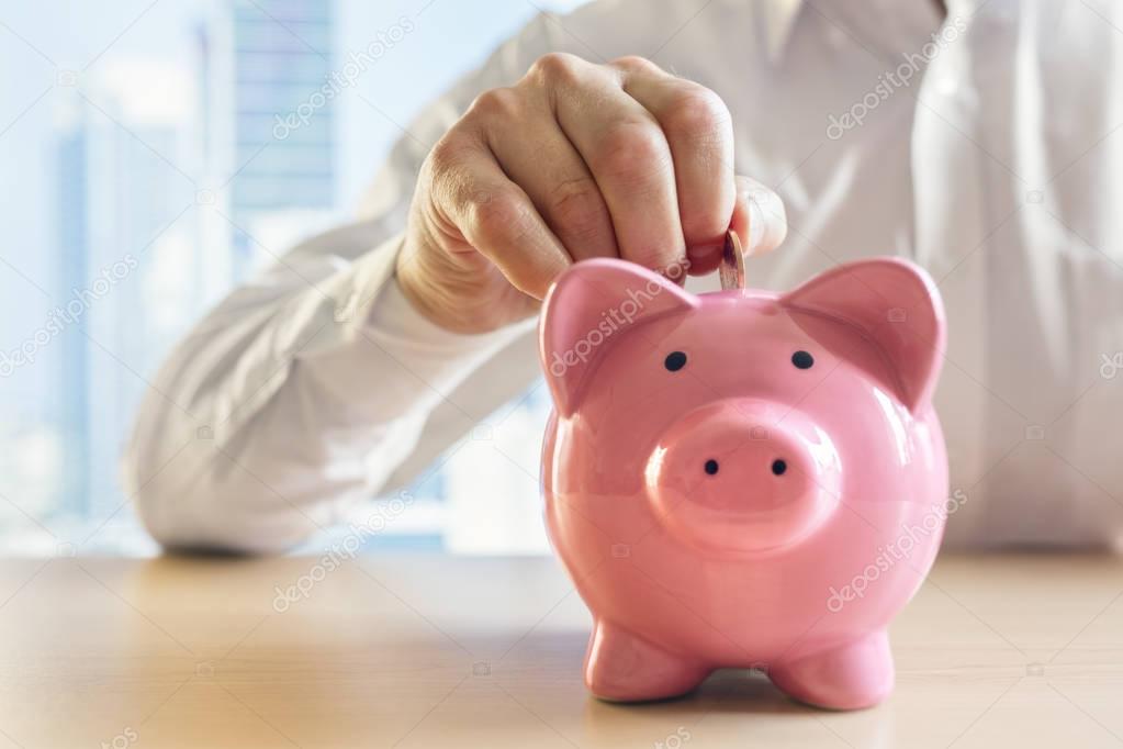 Man putting  coin into  piggy bank 