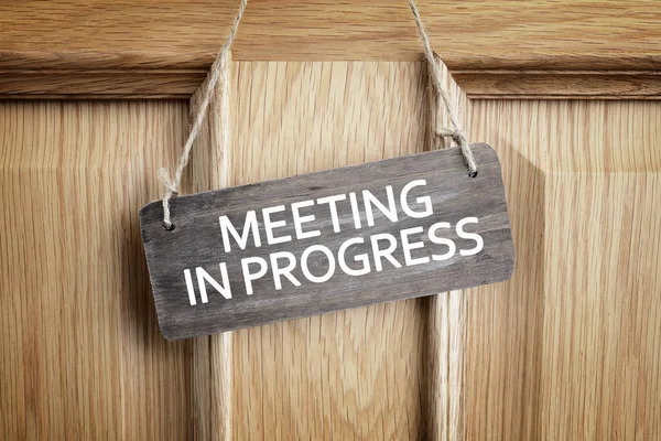 Meeting in progress sign on office door