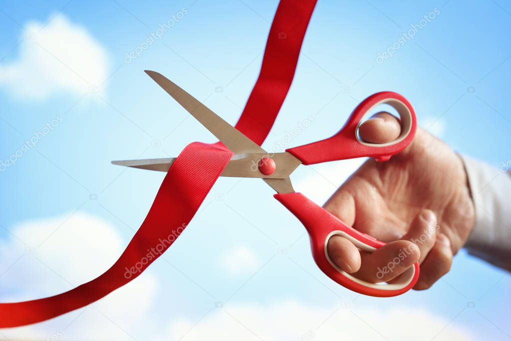 Cutting red ribbon with scissors