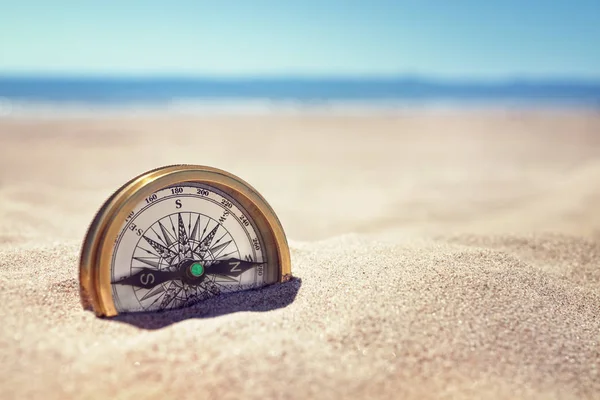 Golden compass in sand — Stock Photo, Image