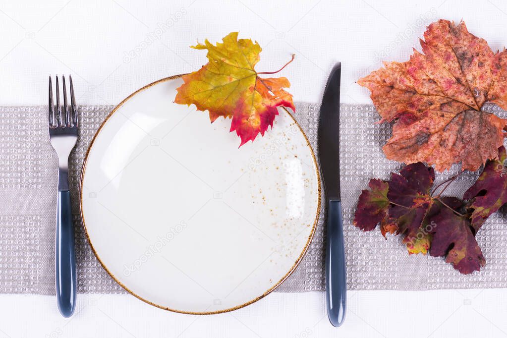 Cozy festive fall table setting with colorful autumn leaves. Minimal restaurant menu concept. Flat lay, top view