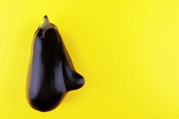 Ugly eggplant with a nose on a yellow paper, minimalism