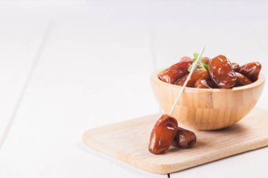 Beyaz arka planda terracotta kasesinde çiğ ve kuru hurma. Sağlıklı beslenmeye organik tatlılar. Ramazan Kareem