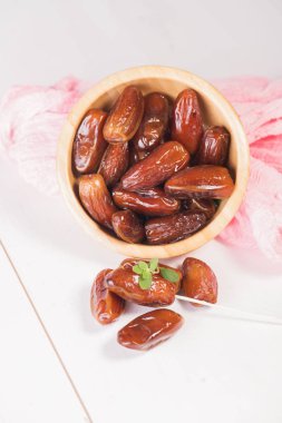 Beyaz arka planda terracotta kasesinde çiğ ve kuru hurma. Sağlıklı beslenmeye organik tatlılar. Ramazan Kareem