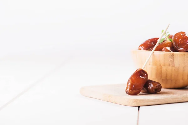 Raw sweet dry dates with in a terracotta bowl on a white background. Organic sweeties to healty eating. Ramadan kareem