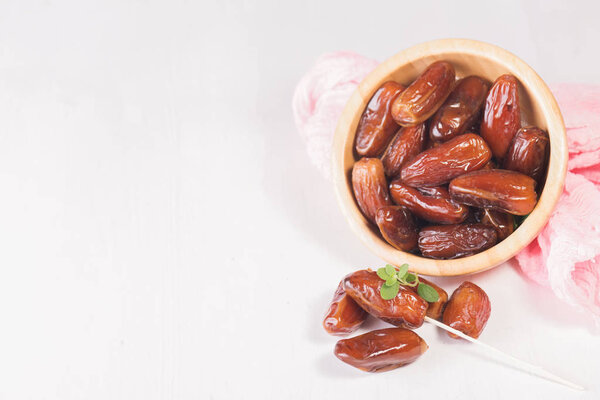 Raw sweet dry dates with in a terracotta bowl on a white background. Organic sweeties to healty eating. Ramadan kareem