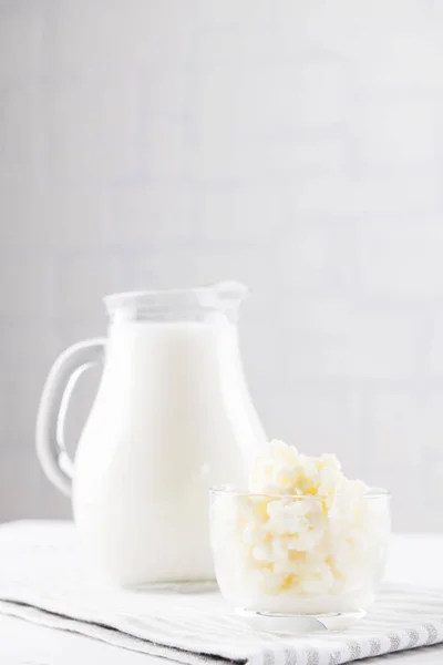 Kefir de bebida fermentada caseiro com grãos de kefir em tigela em um fundo branco, conceito de alimento fermentado natural e saúde intestinal — Fotografia de Stock