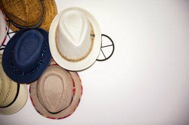 Beyaz bir duvardaki birçok yaz şapkasını kapatın. Otelin beyaz duvarına asılan Hasır Şapkalar. Aksesuarlar ve seyahat konsepti