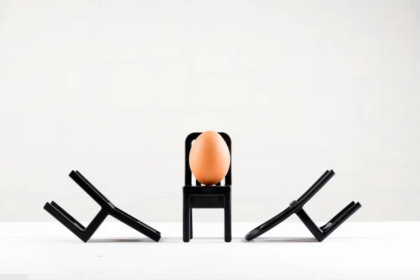 Ένα αυγό κάθεται σε μια μαύρη καρέκλα. Σχεδιασμός επιχειρηματικών ιδεών. Έννοια της ατομικότητας, αποκλειστικότητα. Minimale easter concept — Φωτογραφία Αρχείου