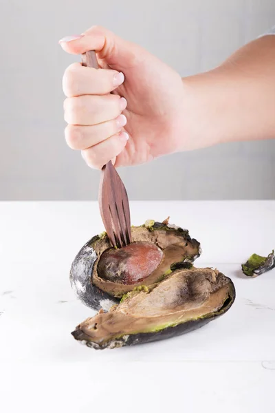 Woman puts rotten avocado on a fork. concept of stop wasting food, don\'t waste food in supermarket and at home