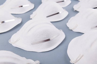 Gri bir arka planda beyaz yüzlü tıbbi maske deseni. Sağlık ve koronavirüs önleme kavramı. Yüz maskesi kirliliğe, virüse, gribe ve enfeksiyonlara karşı koruma