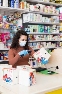 Avetrana, İtalya, Marth, 13, 2020. Süpermarkette çalışan tıbbi maskeli ve eldivenli genç ve güzel bir kasiyer. Coronavirus sırasındaki sağlık standartlarına saygı, karantina covid-19
