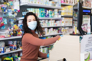 Avetrana, İtalya, Marth, 13, 2020. Süpermarkette çalışan tıbbi maskeli ve eldivenli genç ve güzel bir kasiyer. Coronavirus sırasındaki sağlık standartlarına saygı, karantina covid-19