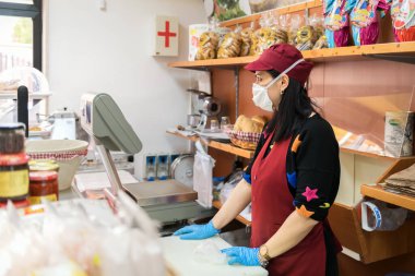 Avetrana, İtalya, Marth 16, 2020. Satıcı kadın, Coronavirüs epidemisi sırasında tıbbi maske ve eldiven takarak daha iyi zamanları bekliyor. Alışveriş, Covid-19 pandemisi, karantina