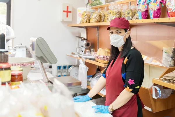 Avetrana, İtalya, Marth 16, 2020. Satıcı kadın, Coronavirüs epidemi sırasında tıbbi maske ve eldiven takarak müşteri bekliyor. Alışveriş, Covid-19 pandemisi, karantina