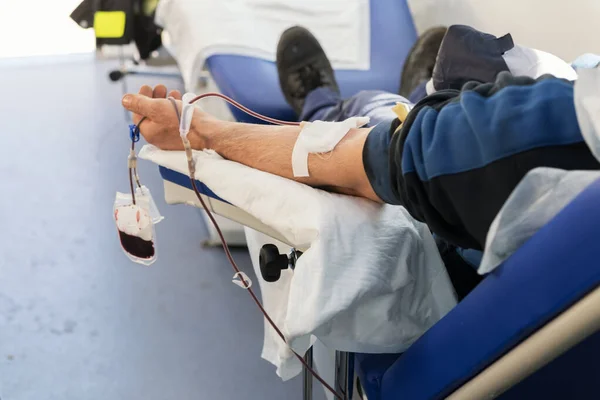 Une main de donneur assis sur un fauteuil dans une banque de sang mobile pendant la collecte de sang. Don pour soutenir les hôpitaux pendant le coronavirus — Photo