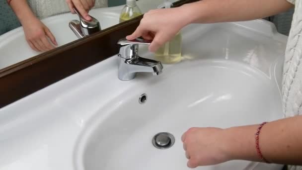 Hands of a beautiful woman wash their hands in a sink with foam to wash the skin and water flows through the hands. Concept of health, cleaning and preventing germs from contacting hands and beauty — Stock Video