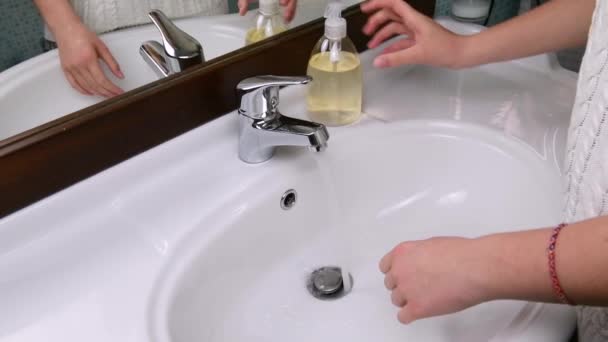 Les mains d'une belle femme se lavent les mains dans un évier avec de la mousse pour laver la peau et l'eau coule à travers les mains. Concept de santé, nettoyage et prévention des germes de contact mains et beauté — Video